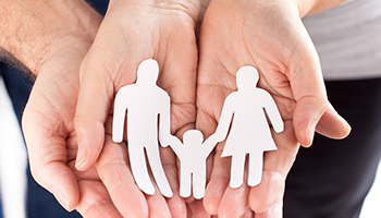 A family holds colorful paper cutouts representing their family members