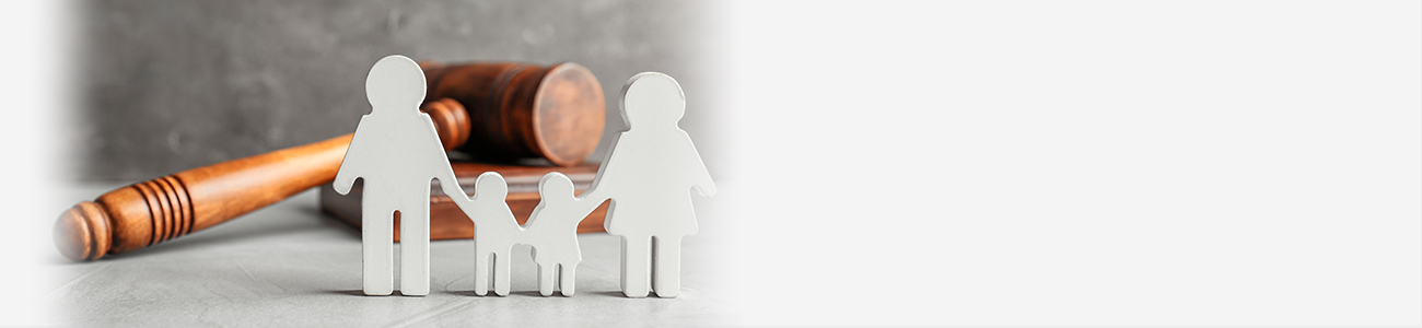A wooden gavel rests beside figurines representing a family